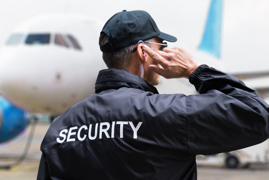 Security Guard Listening To Earpiece Against Building