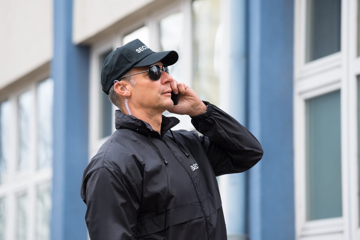 Security Guard Using Mobile Phone Outside Building