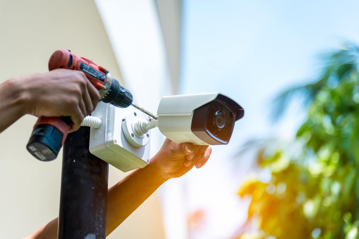 A Wireless CCTV camera setting outside building with white box water poof with sun blur background.