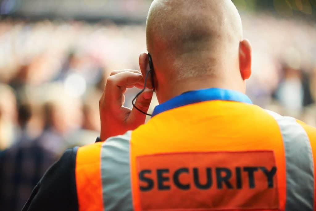 Calgary security company guard with an ear piece surveying a venue that's blurred out. 